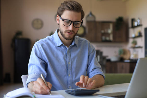 istock Happy young business man is analizing financial documents from home during self isolation. 1226764421