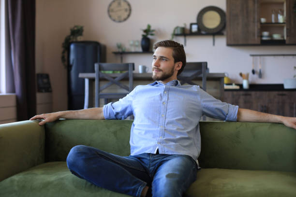 istock Handsome young business man is looking relaxed while sitting on the couch at home. 1226764802