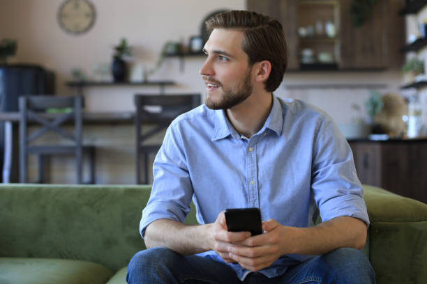 istock Attractive young man relaxing on a couch at home and using mobile phone for cheking social nets. 1226764811