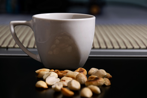 Coffee and peanuts (roasted without salt) on a notebook screen, side view.