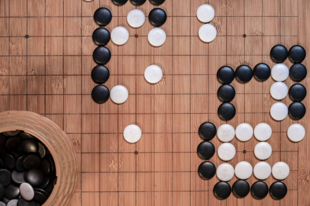 istock Go board game playing. A competitor is placing a marble piece on a Go board game, Hand playing black and white stone pieces on 1226765899
