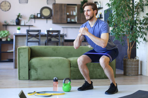 istock Handsome man doing squats exercise at home during quarantine. Concept of healthy life. 1226765933