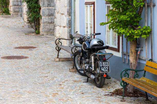 Hallstatt, Austria - May 22nd 2020: An old Puch motorcycle parked in front of a residential building at Hallstatt. It's still having an old black and white number plate from the 1990s ...