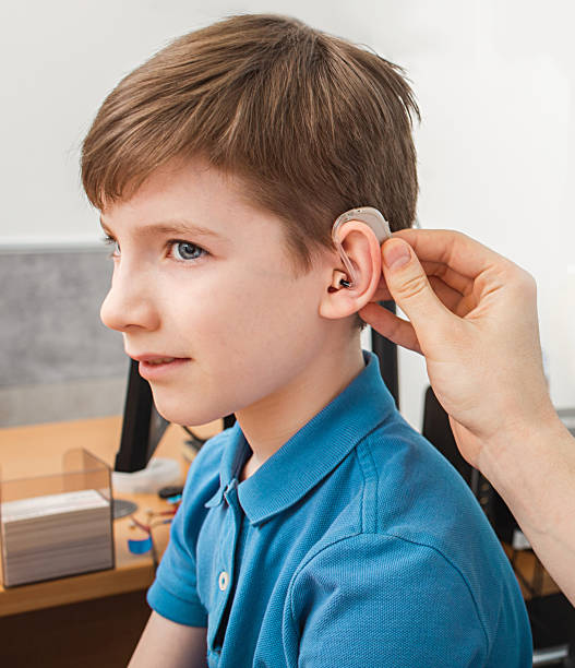 istock Installation hearing aid on 'acasian boy's ear. Hearing solution for kid, hearing treatment 1226770630