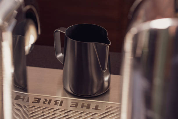 istock Classic matt surface stainless steel milk frothing pitcher mug with handle sit on table.  Kitchen tool, heat-resistant and durable. 1226773603