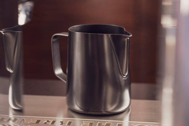istock Classic matt surface stainless steel milk frothing pitcher mug with handle sit on table.  Kitchen tool, heat-resistant and durable. 1226773608