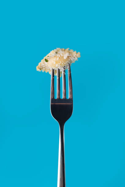 istock Ravioli with parmesan on a fork isolated on a blue background. 1226773872