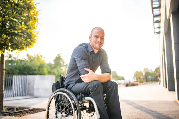 Photo of Outdoor Portrait of Relaxed Young Businessman in Wheelchair