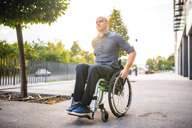 istock Businessman in Mid 20s Rolling Along Pathway in Wheelchair 1226774903