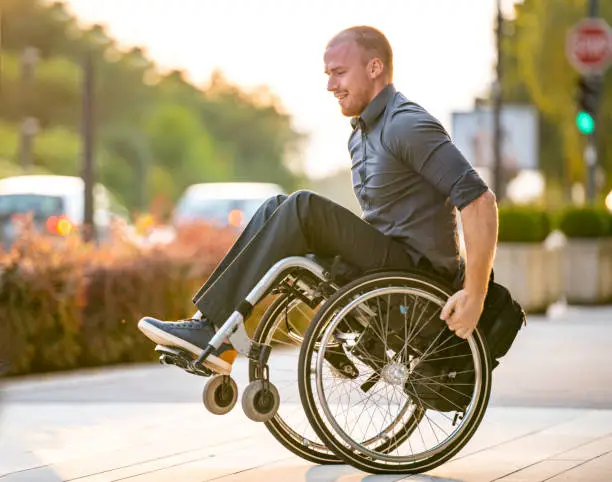 Lens flare view of Caucasian male business professional in mid 20s Doing Stunts with Wheelchair for fun-