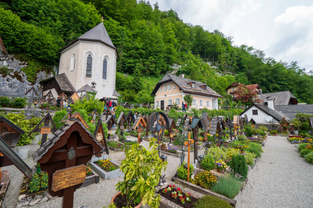 view of the cemetery surrounding the roman catholic parish church of hallstatt, salzkammergut region, oö, austria, with the famous charnel house - people cemetery church urban scene imagens e fotografias de stock