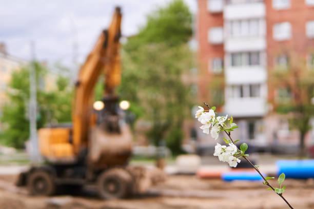twig of a blossoming apple tree and a blurry working excavator in the background