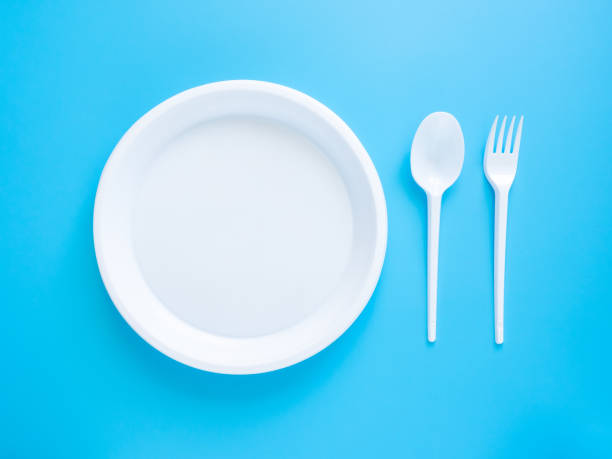 istock Plastic white plate, fork and spoon isolated on a blue background. Disposable cookware for picnics. The concept of protecting the environment from plastic contamination. Problems of the world ecology 1226776701