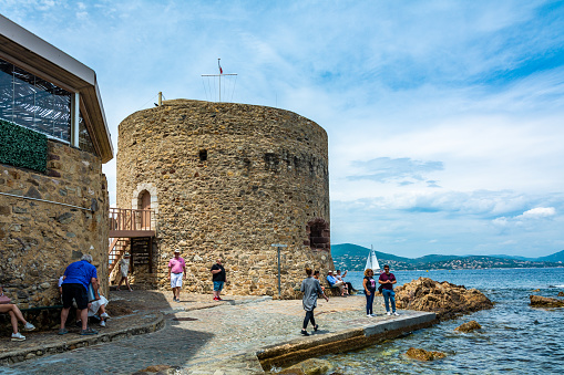 Saint-Tropez, France - June 11, 2019 : The 15th Century Portalet Tower stands at the beginning of the great pier and is overlooking the creek of La Glaye in Saint-Tropez, Var, France.