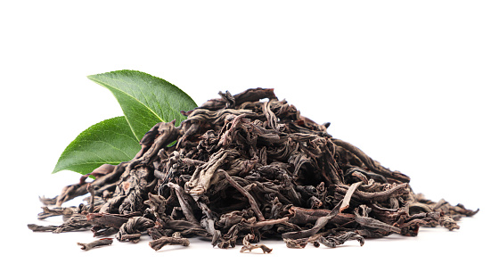 A slide of black tea with green leaves close-up on a white background. Isolated