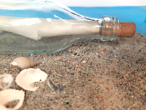 Message in a Bottle. Decorative background with a bottle on the sand with a sheet of paper for posting. Marine themes for decorating and creating collages and moods.