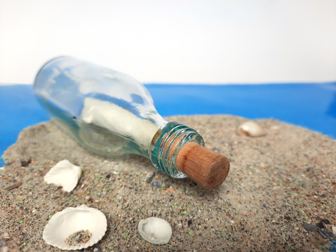 Message in a Bottle. Decorative background with a bottle on the sand with a sheet of paper for posting. Marine themes for decorating and creating collages and moods.