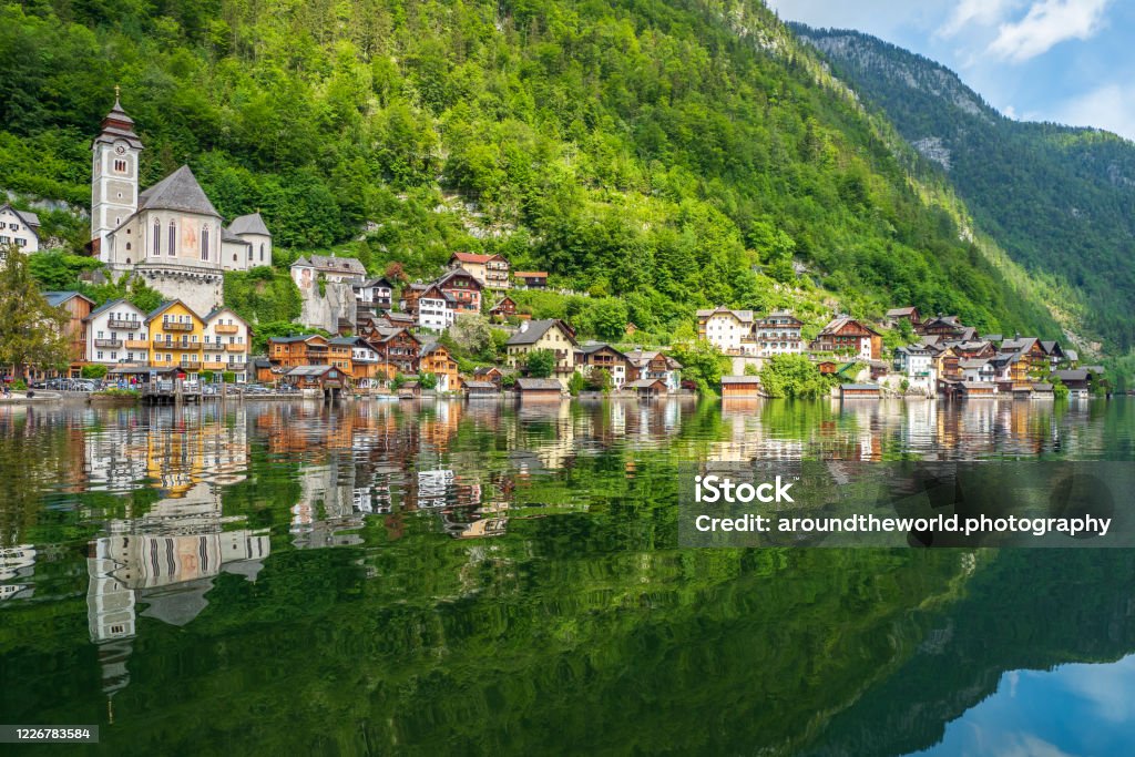 Scenic view of the famous mountain village Hallstatt in the Salzkammergut region, OÖ, Austria Hallstatt, Austria - May 22nd 2020: Hallstatt, the famous mountain village reflecting beautifully in the tranquil water of Lake Hallstatt. Picture taken from a boat on lake Hallstatt. Austria Stock Photo