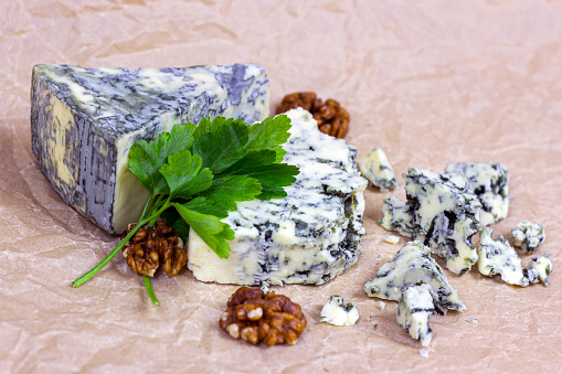 Slices and triangles of Danish Blue (dorblue) cheese with mold on light background.