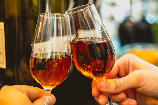 Jerez-Xeres-Sherry wine toast at foreground holding by hands and bottles at background in a spanish bar