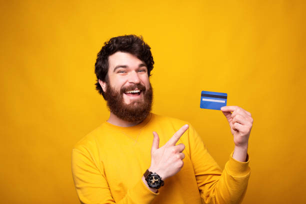 istock Pay with cards. Bearded man holding one is pointing at it and smiling at the camera. 1226793609