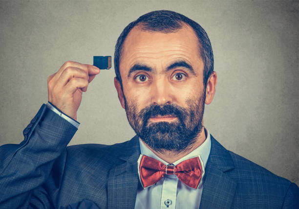 istock man wearing elegant jacket and red bow tie holding Micro SD card near his head 1226794669