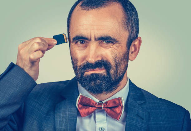 istock man wearing elegant jacket and red bow tie holding Micro SD card near his head 1226794725