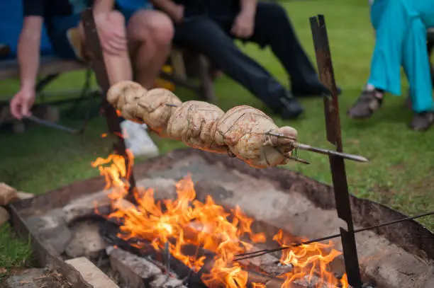 Photo of whole chicken on an open fire, on a spit.