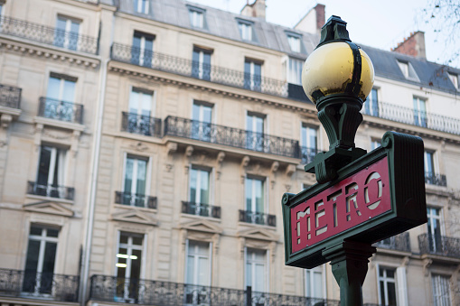 The Paris Metro sign with a light, indicating the presence of the subway system entrance.