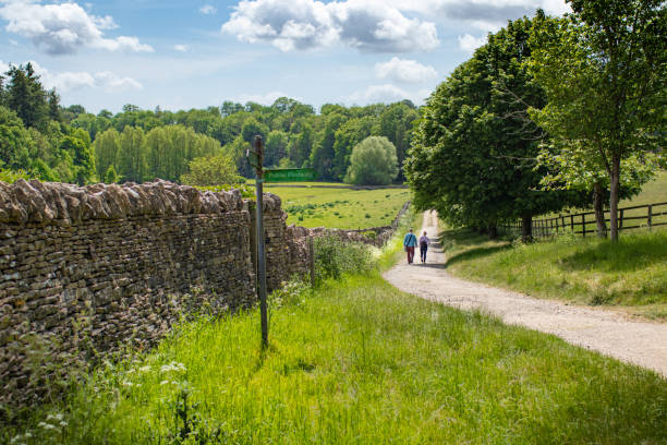 casal dando um passeio por um longo caminho de freio na deslumbrante paisagem de cotswold perto de bibury em cotswolds, enquanto o bloqueio covid 19 relaxa no final de maio - bridle path - fotografias e filmes do acervo