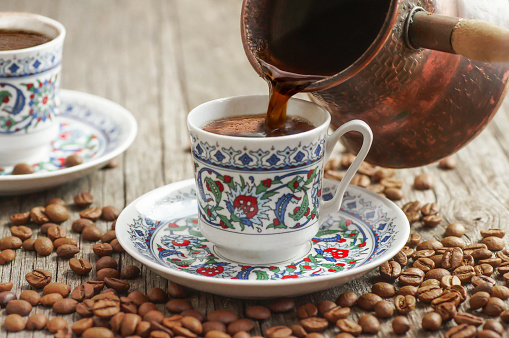 café turco tradicional en la taza de porcelana vertiendo de la olla de café de cobre, concepto de bebida caliente photo