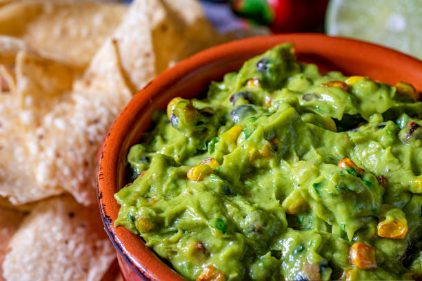 istock Fresh guacamole in red clay dish with corn tortilla chips and raw ingredients. 1226807749