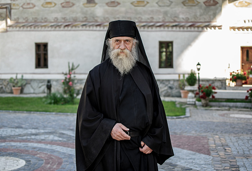 Monk dressed in black and with a white beard. Lainici Monestery, Romania. May, 23, 2020