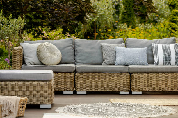 istock Grey pillows on trendy wicker L shape sofa in the green garden 1226810759
