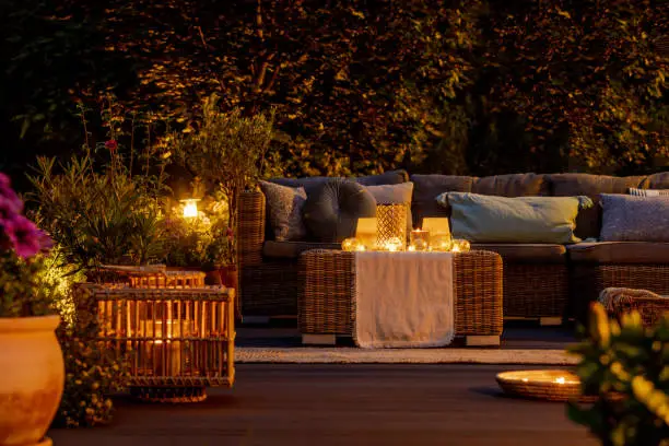Photo of Trendy furniture, lights, lanterns and candles in the garden at night