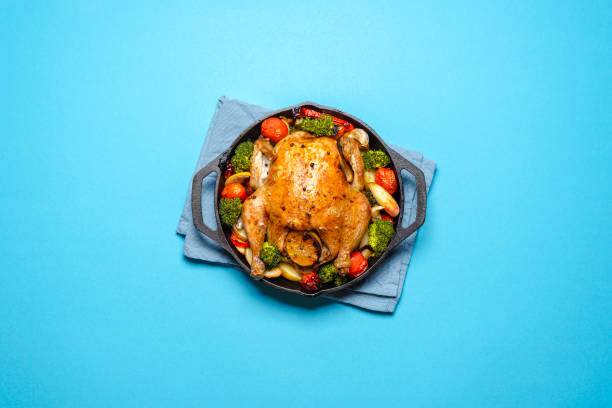 Roasted chicken with vegetables in an iron cast, top view.