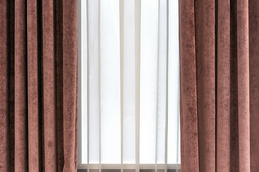 Brown velor curtains and white tulle on the window in the living room.