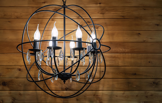 Black metal chandelier with bulb-candles and crystal pendants.