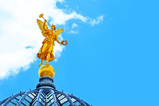 Dresden, Germany- June, 2019: Famous golden statue of Pheme or Fama on the roof of the Dresden University of Visual Arts, Kunstakademie. Sculpted by Robert Henze. Zitronenpresse, lemon squeezer