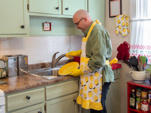 istock Man in frilly apron washing dishes 1226818383