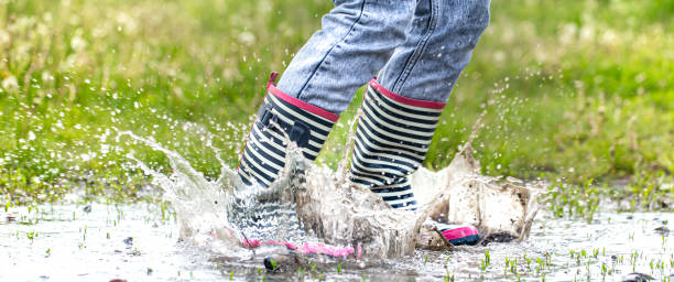 istock A child in rubber boots jumps in a puddle. 1226819670