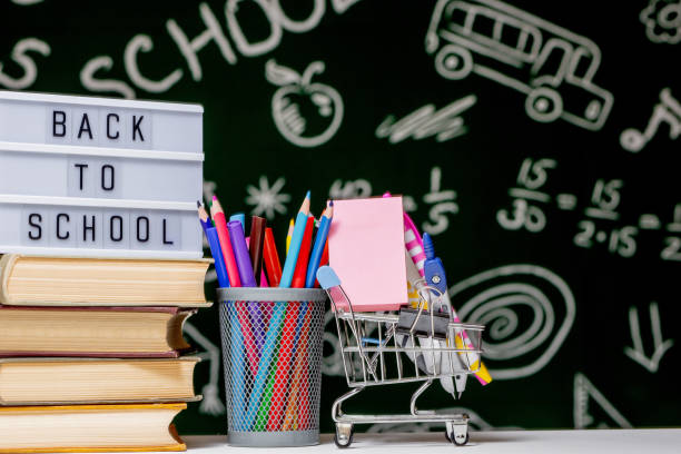 istock Back to school background with books, pencils and globe on white table on a green blackboard background. 1226820521