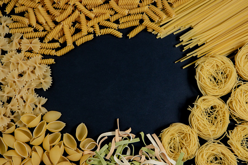 Assortment of different types of pasta dry on black background