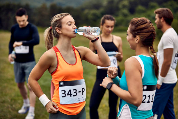 istock Marathon runner drinking water while talking to her friend in nature. 1226822789