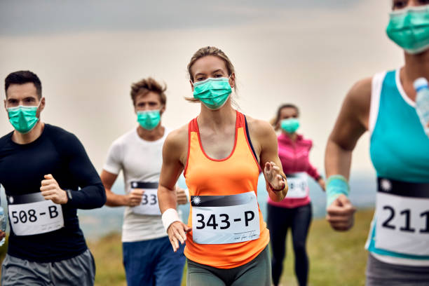 grupa wysportowanych ludzi biegających maraton podczas noszenia ochronnych masek na twarz. - jogging running motivation group of people zdjęcia i obrazy z banku zdjęć