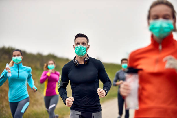 atletyczny mężczyzna ubrany w ochronną maskę na twarz podczas udziału w maratonie. - jogging running motivation group of people zdjęcia i obrazy z banku zdjęć