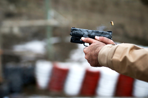 A woman learns to shoot a pistol at a shooting range with an instructor
