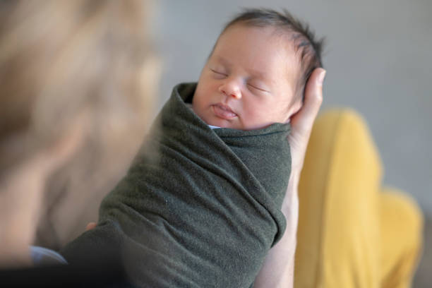 彼女の揺れた新生児を抱く白人の母親 - baby blanket ストックフォトと画像