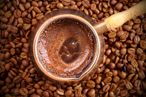 café turco tradicional en la cafetera de cobre en granos de café, concepto de bebida caliente photo