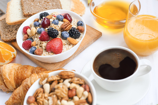 Healthy breakfast with muesli, fruits, berries, nuts, coffee, eggs, honey, oat grains and other close up